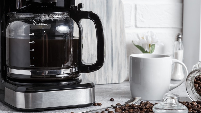 black coffee maker and white coffee cup