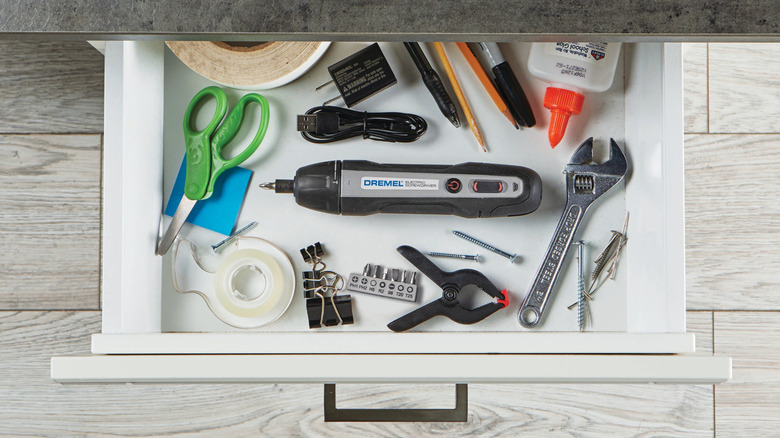 A Dremel power screwdriver inside a drawer next to other tools.