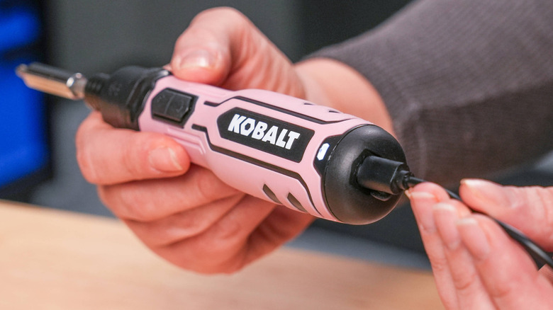 A pink Kobalt power screwdriver plugged into a charger.
