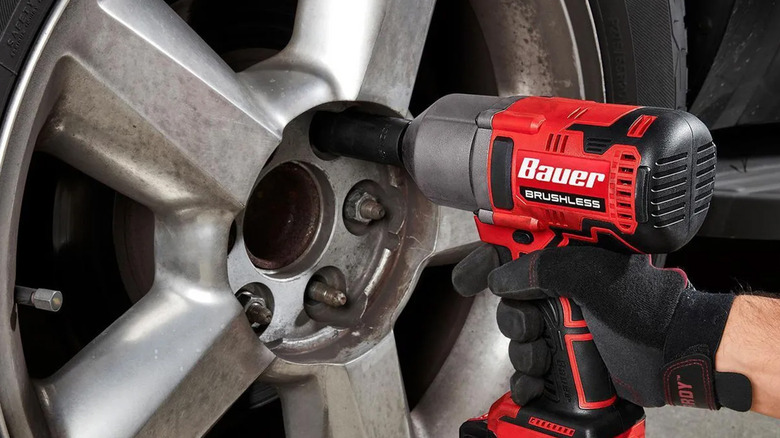 A Bauer brand impact wrench loosening lug nuts on a wheel