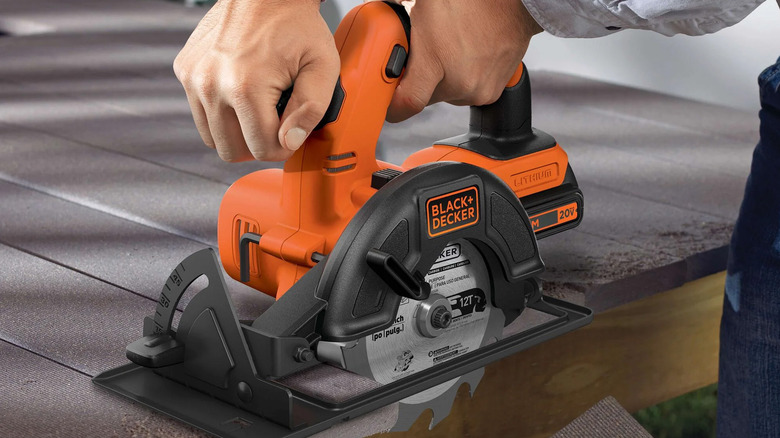 A man using a Black and Decker circular saw on planks of wood