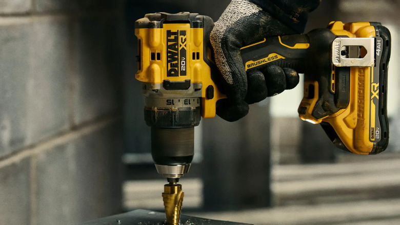 A worker using a drill to bore a hole into a piece of metal