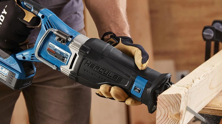 A man sawing through wood with a reciprocating saw