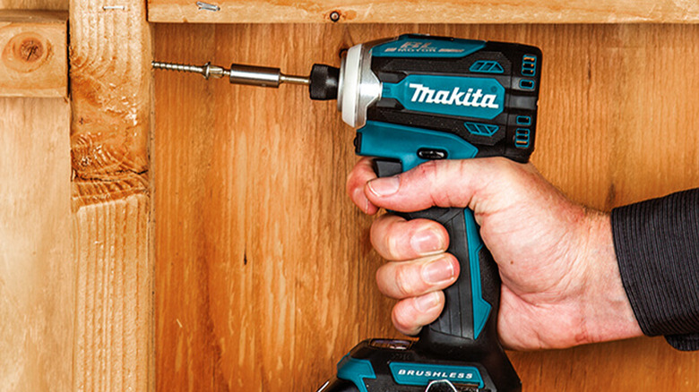 A man screwing in a screw into wood
