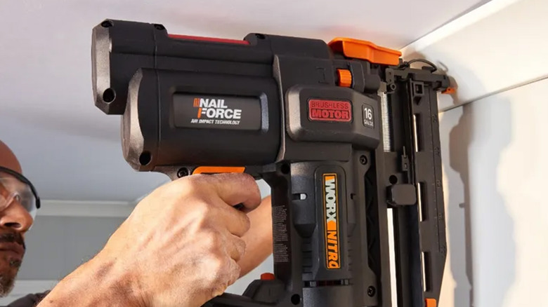 A man using a Worx nail gun to attach siding to a house