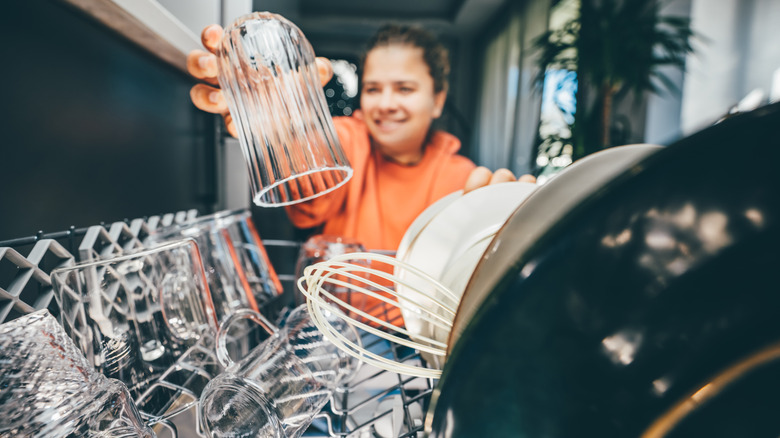 blurred woman loading in focus dishwasher