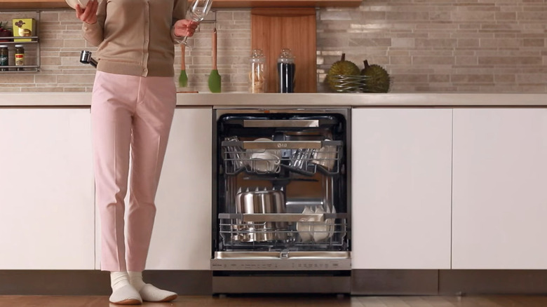 Woman with dishes standing next to an open LG dishwasher