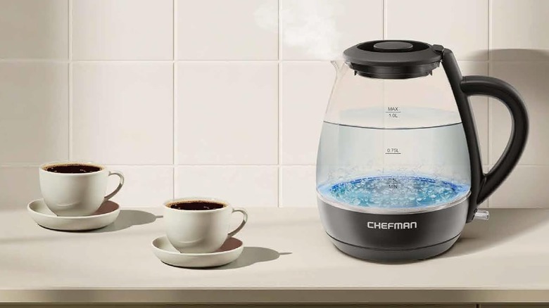 Chefman electric kettle sitting on a countertop next to two full cups
