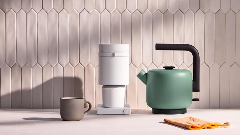 Fellow Clyde electric kettle on a countertop with another appliance and coffee cup