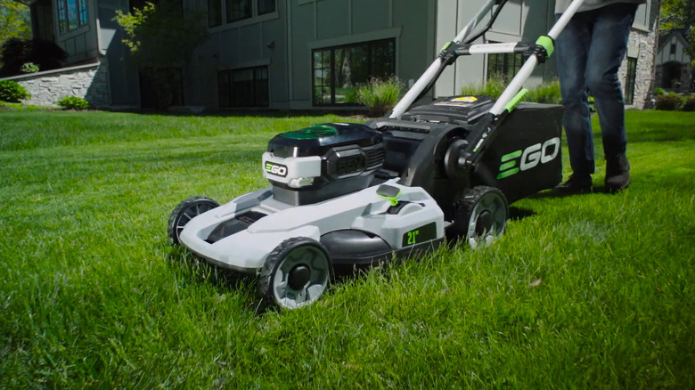 Ego electric lawn mower being pushed in a front yard