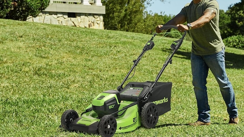 Greenworks lawn mower being used and pushed on the side a hill