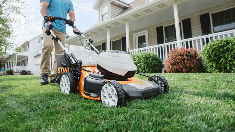 Man pushing the Stihl lawn mower in the front yard of a house
