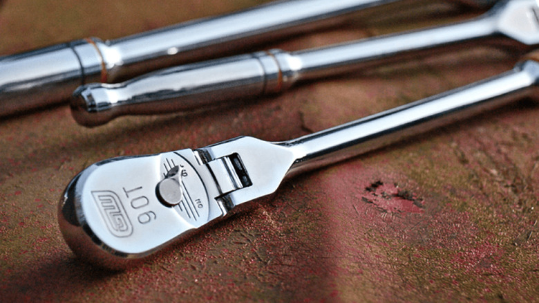 Three Gearwrench brand ratchets on a rusty piece of metal