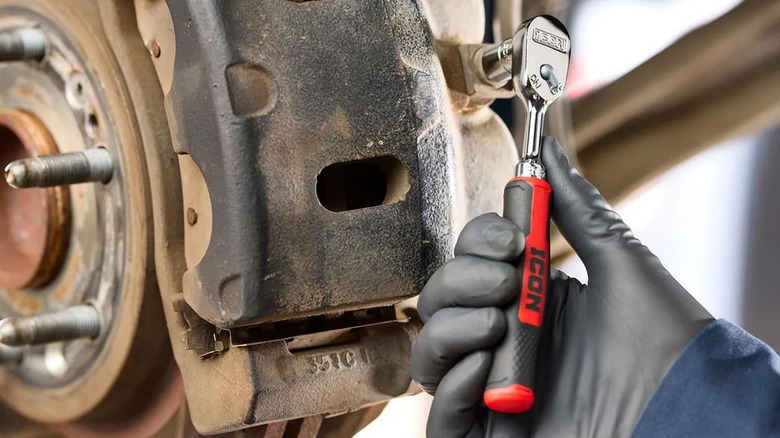 A mechanic using an Icon ratchet on a car brake system