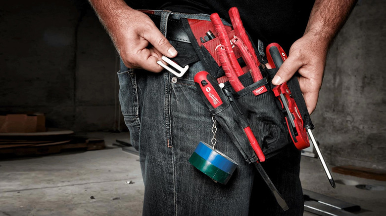 A handyman with a belt carrier that has several Milwaukee tools in them