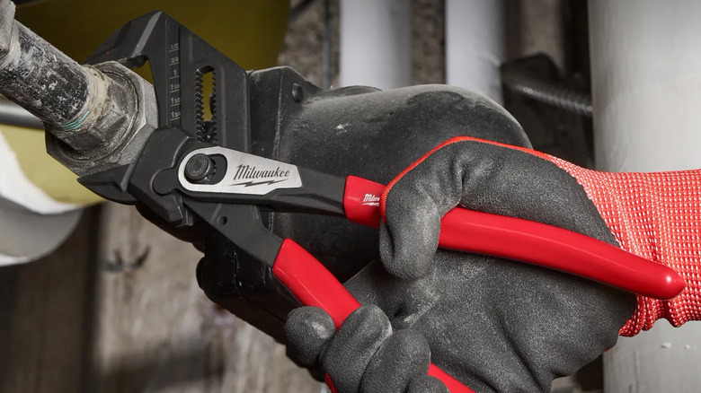 A person using a Milwaukee pliers wrench to tighten a water pipe