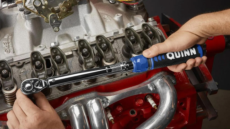 A man tightening pieces of a car engine that's painted red
