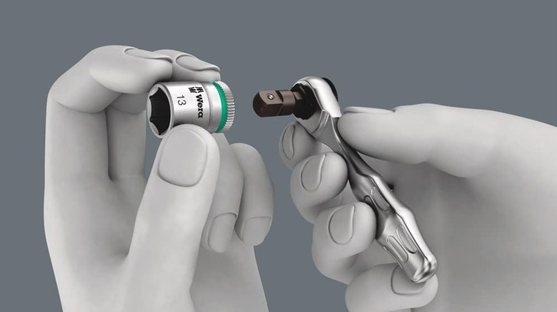 A computer rendering of two hands holding a Wera ratchet and socket