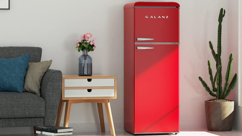 A red Galanz fridge in a living room next to a sofa