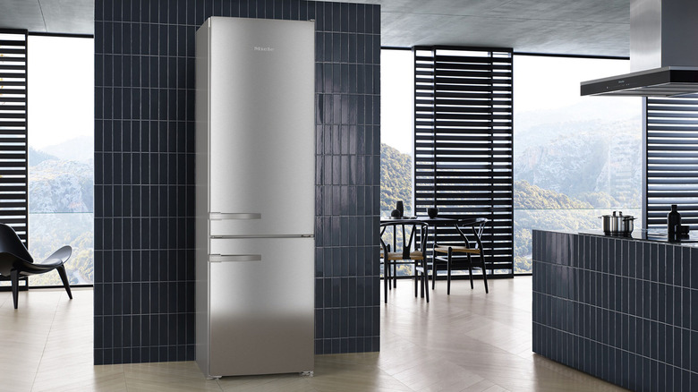 A Miele fridge in a black tiled kitchen