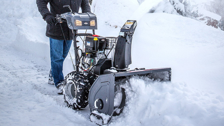 A person operating a black Briggs and Stratton Murray snow blower