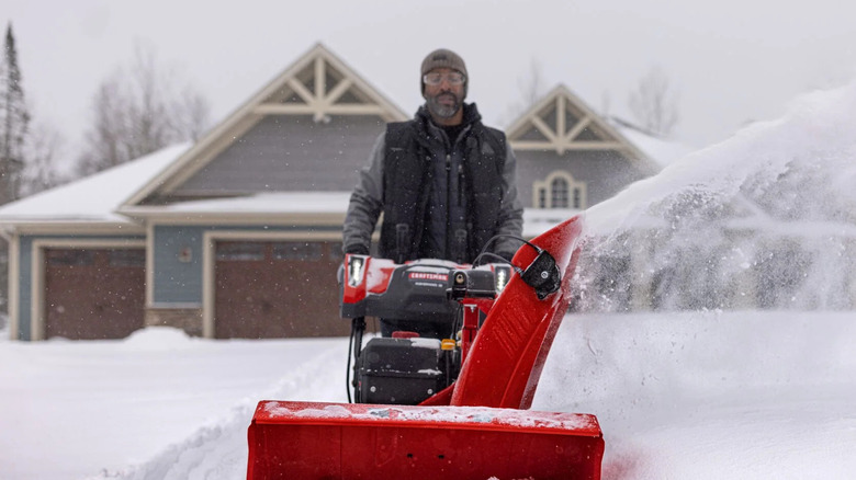 A person operates a red Craftsman snow blower in thick snow