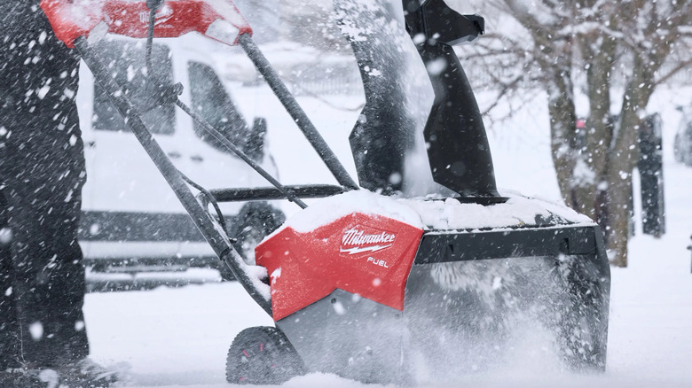 A Milwaukee snow blower in use, the user is out of frame
