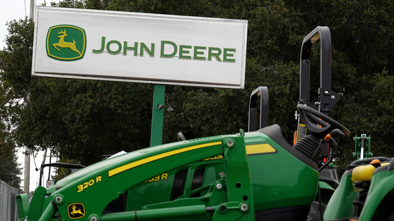 A John Deere tractor beside a John Deere sign