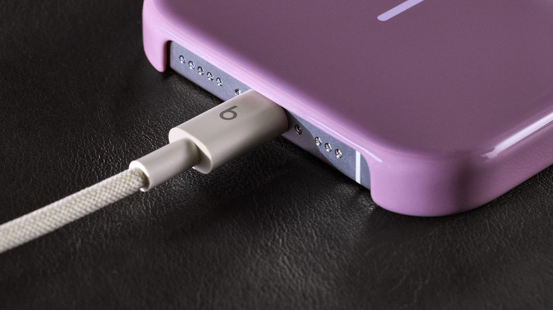 A white braided Beats USB-C cable connects to a smartphone.