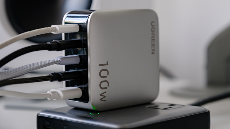 A Ugreen 100W multiport charger has five black and white USB-C cables connected to its ports.