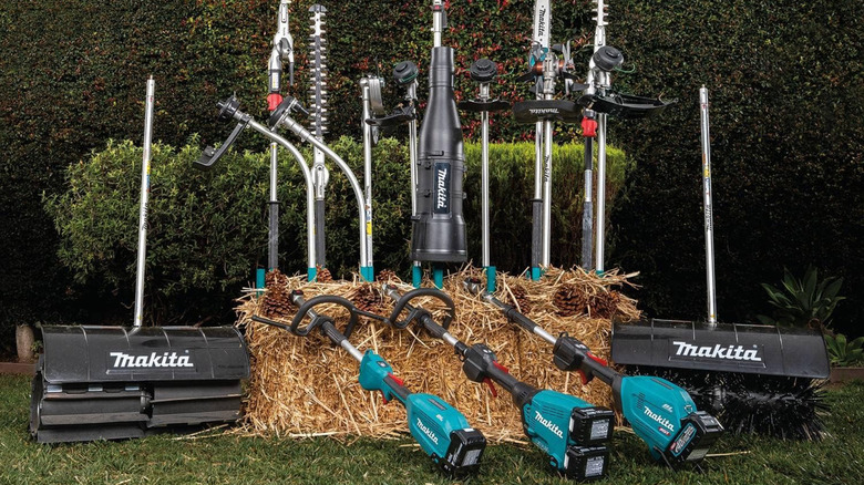 Many different Makita couple shaft attachments and power heads in a garden.