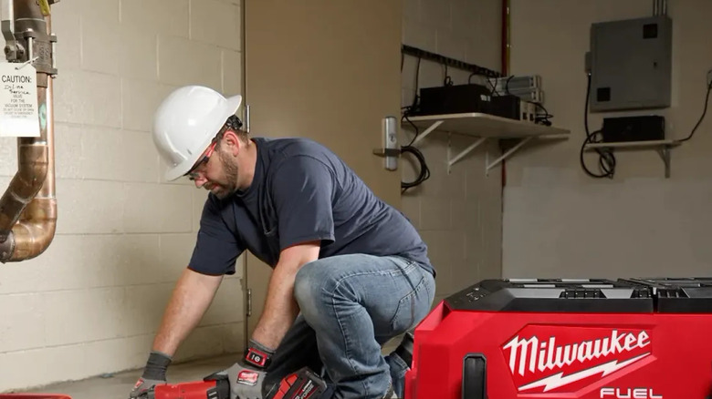 A man uses the M18 Fuel 9 Gallon Dual-Battery Dust Extractor by Milwaukee on a sander
