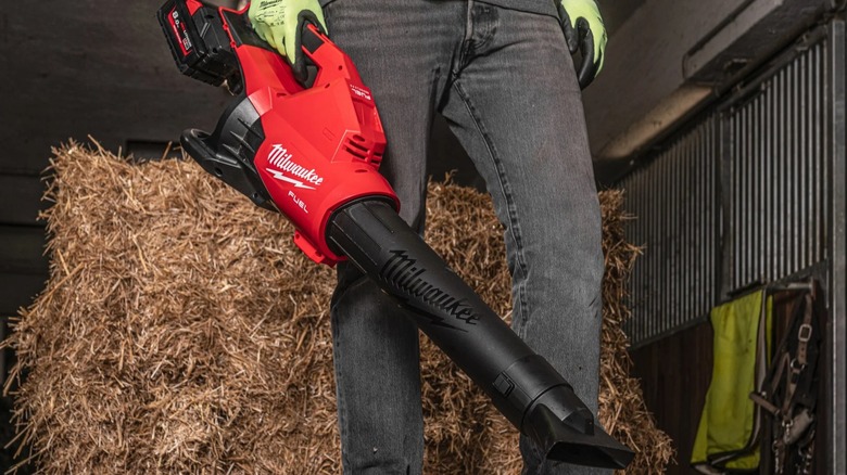A person holds the Milwaukee M18 Fuel Dual-Battery Blower with a hay bale in the background