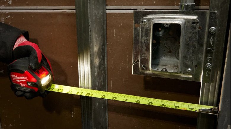 Person using tape measure with light attached