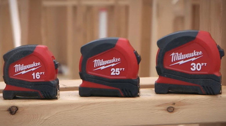 Three tape measures on a piece of lumber