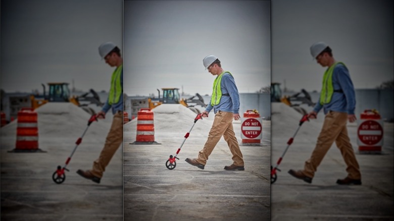 person walking behind measuring wheel
