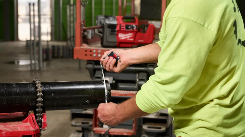 Person using tape measure on large pipe