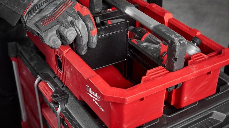 A person wearing gloves places dividers inside a Packout Tray