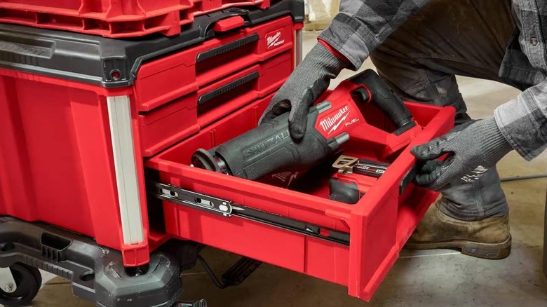 A person opens the larger drawer of the Packout Multi-Depth 3-Drawer Tool Box and places a large power tool inside