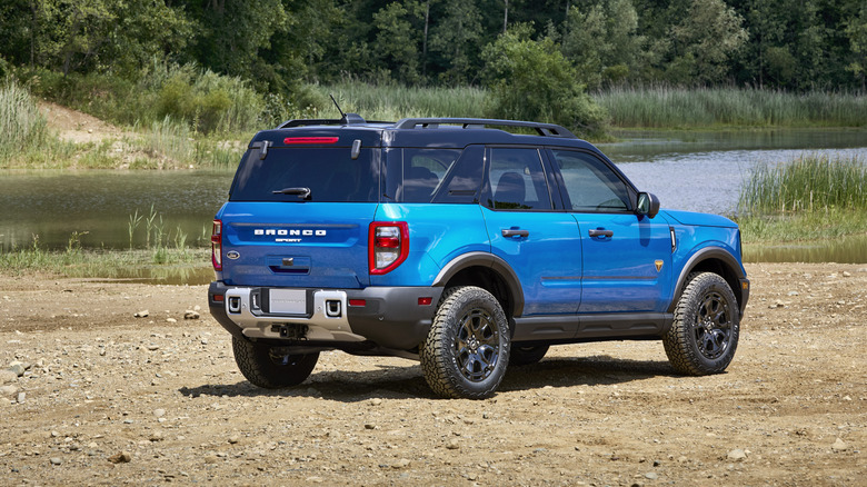 Blue 2025 Ford Bronco Sport SUV parked near a river, seen from right rear