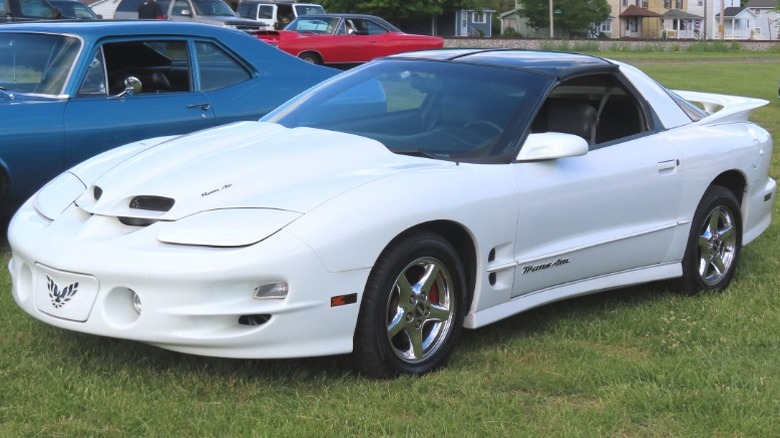 White 1998 Pontiac Firebird Trans Am parked on grass at a car show