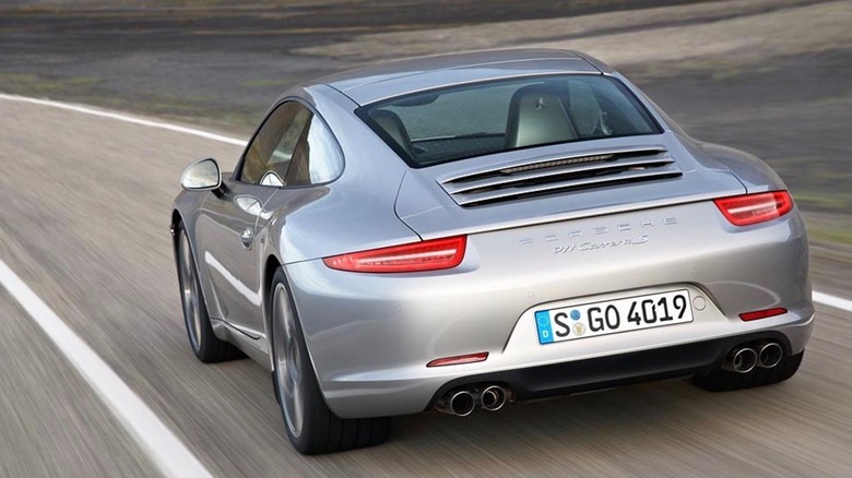 A silver Porsche Carrera S moving away from the camera on a road at speed.