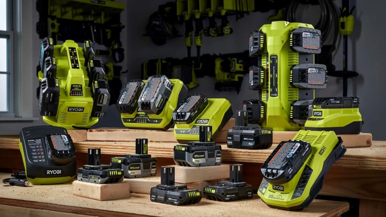 Several Ryobi batteries on lumber, some slotted in green Ryobi chargers