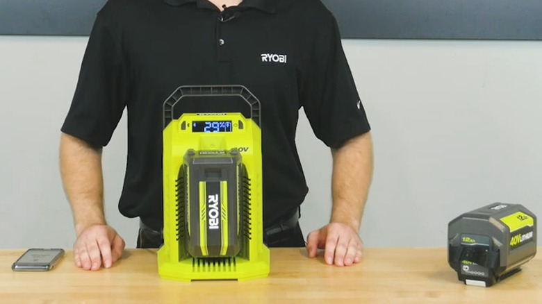 A person presenting the Ryobi 40V Hyper Charger on a table