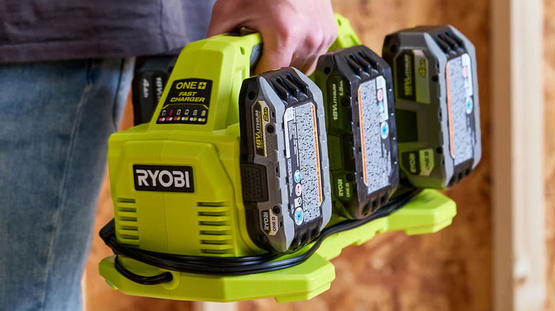 A person holding the Ryobi One+ 18V 6-Port Fast Charger with batteries attached