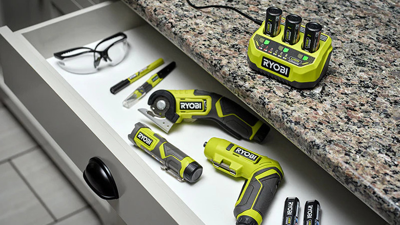 Ryobi tools in a drawer with a battery charger on the countertop