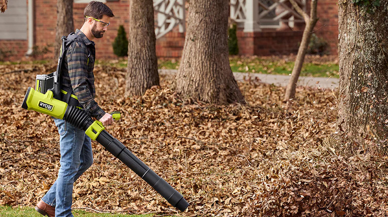 A man clearing many leaves with a Ryobi backpack blower