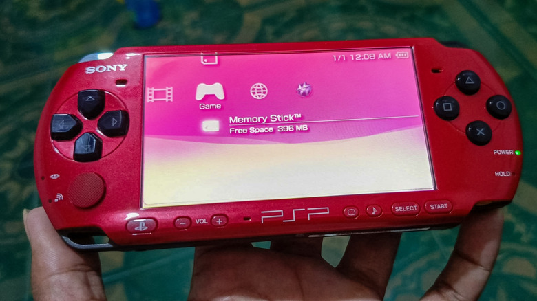 A person holding a red PlayStation Portable