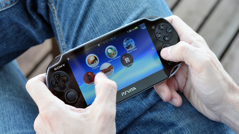 A person wearing jeans using the PlayStation Vita