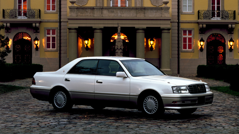 White Toyota Crown parked near a big house